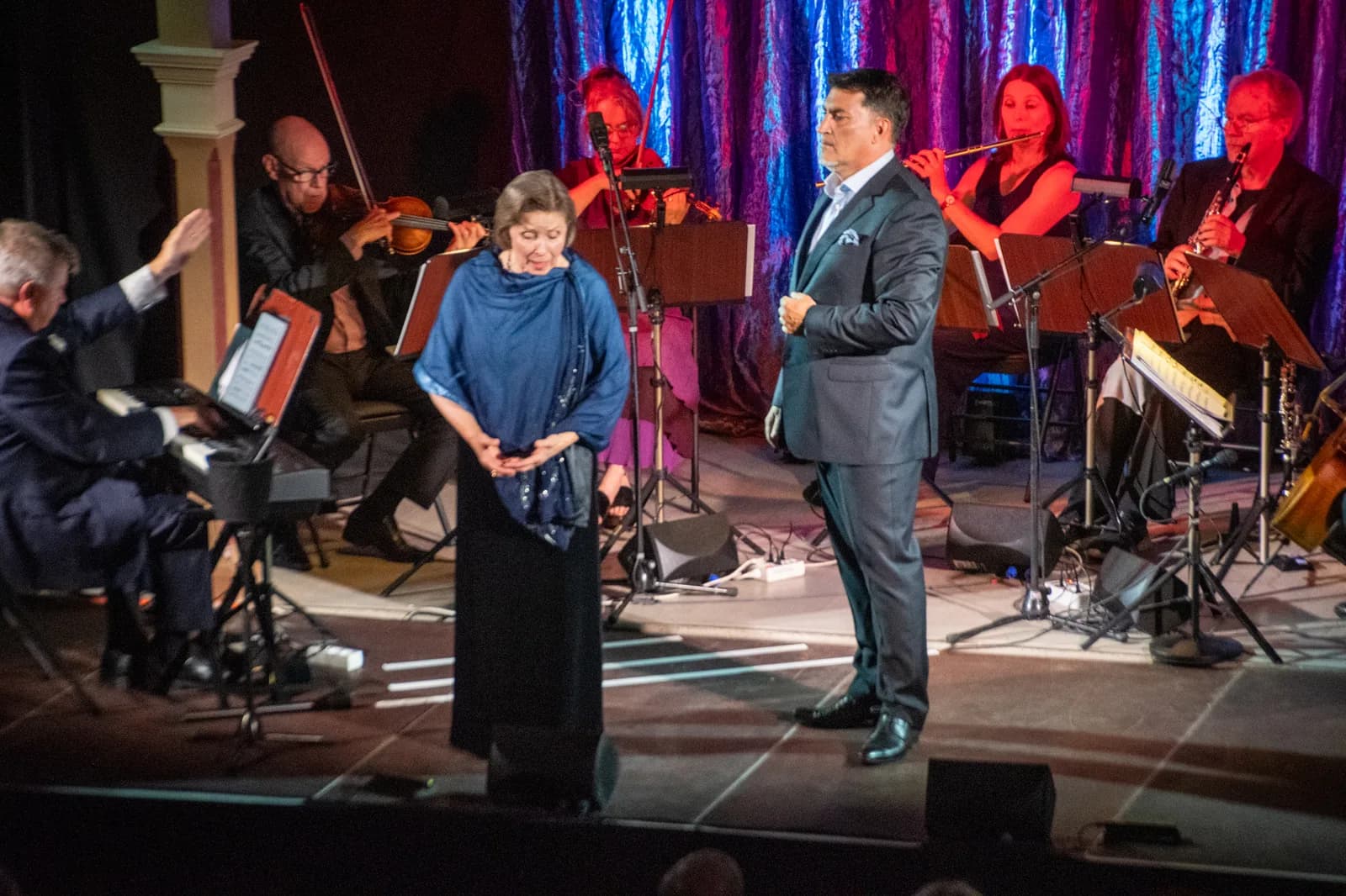 Ann-Christine Larsson och Marco Stella på scenen i Societetshuset på Marstrand, med stråk och blås bakom sig