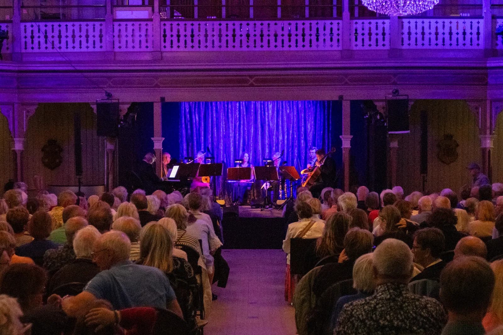 Konsertsalen i Societetshuset på Marstrand sedd från salongen, med publik, scen och balkongen ovanför