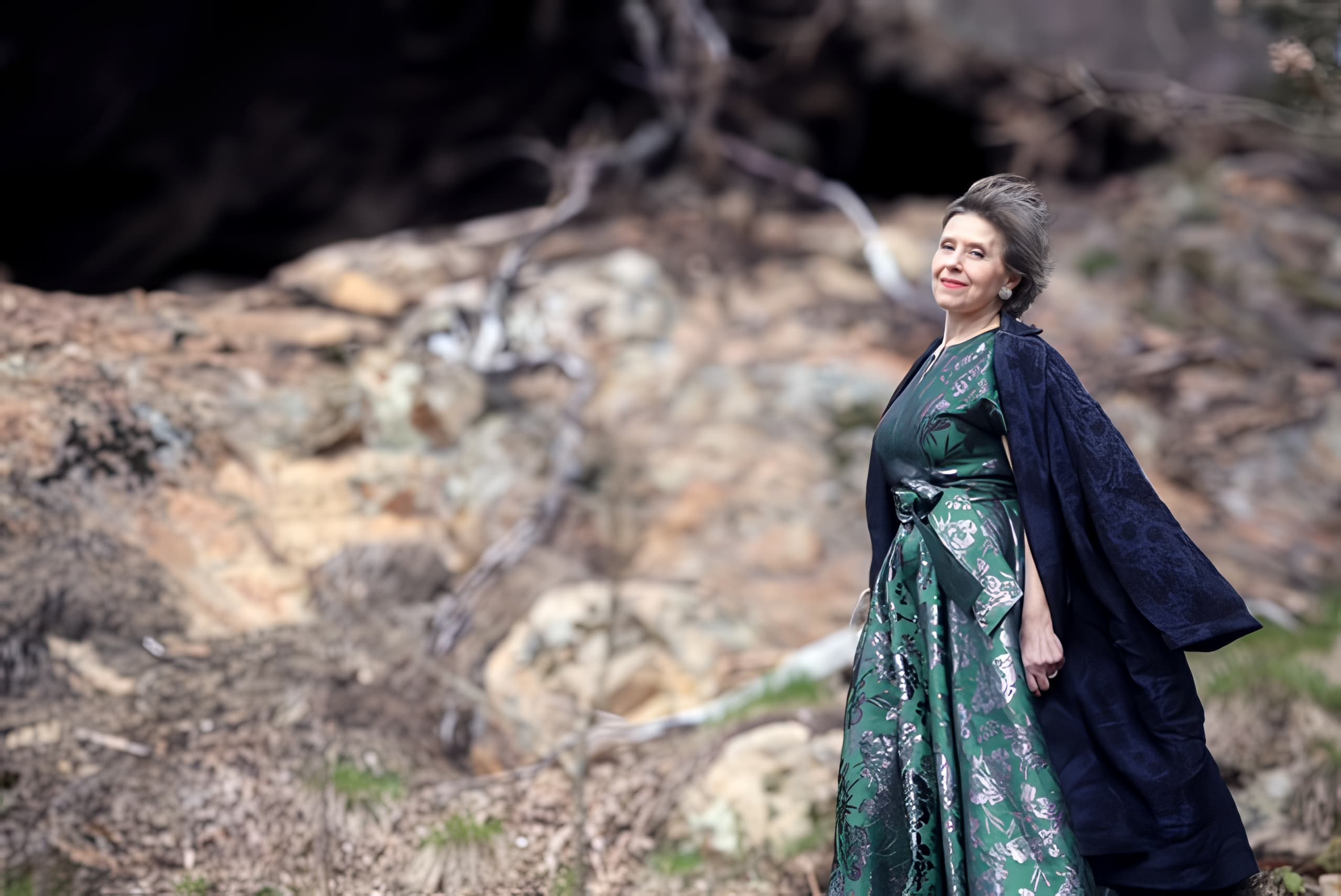 Ann-Christine Larsson standing on rocks outdoors with flowing cape